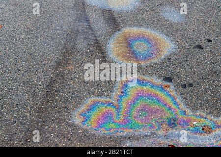 Taches de gaz colorées sur une route d'asphalte. Chenilles de pneus visibles. Banque D'Images