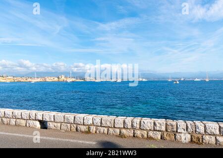 Vue depuis une rue en bord de mer sur la Côte d'Azur de la baie, de la mer et de la ville d'Antibes, France. Banque D'Images