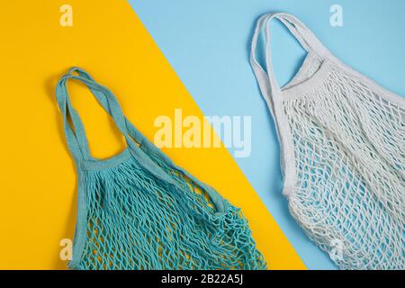 Concept zéro déchet. Deux sacs à provisions en mesh se trouvent sur un fond bleu jaune. Concept écologique et de réutilisation. Vue de dessus ou plat Banque D'Images