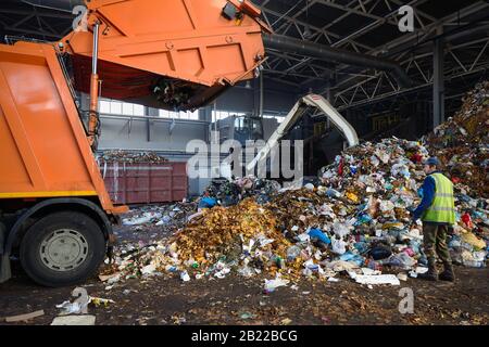 Grodno, BIÉLORUSSIE - OCTOBRE 2018: Travailleur du processus de contrôle des usines de recyclage de déchargement des déchets du camion à ordures. Le manipulateur charge les déchets sur le transport Banque D'Images