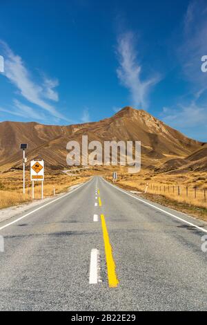 La longue ligne droite de la route en bitume Lindis Pass en Nouvelle Zélande Banque D'Images