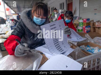 (200229) -- SANMENXIA, le 29 février 2020 (Xinhua) -- les membres du personnel d'une plateforme de commerce électronique trient les légumes selon les commandes d'un centre de tri, à Sanmenxia, dans la province de Henan en Chine centrale, le 28 février 2020. Récemment, Sanmenxia a réalisé un projet visant à assurer l'approvisionnement en légumes pour les résidents par le biais d'un système de distribution communautaire développé par une plate-forme de commerce électronique. La plate-forme transporte les légumes des bases de plantation des agriculteurs locaux vers les communautés résidentielles. Les résidents locaux recueillent leurs commandes séparément. De cette façon, les résidents peuvent acheter des légumes frais avec un « contact zéro » en t Banque D'Images