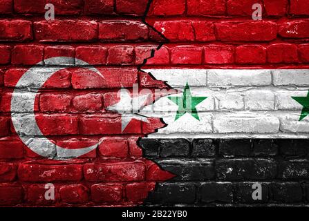 Gros plan, drapeaux de la Turquie contre la Syrie sur un fond de mur de briques fissuré. Concept de crise de guerre et de conflits politiques entre nations Banque D'Images