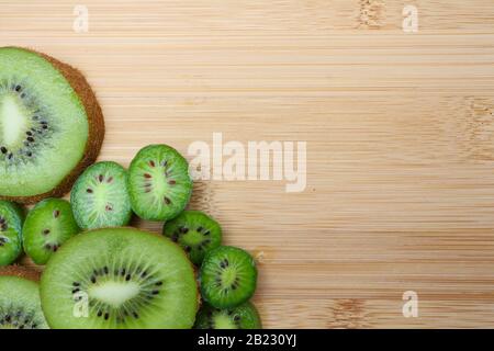 Fruits kiwi en tranches et baies de kiwi disposées sur une planche à découper en bois. Banque D'Images