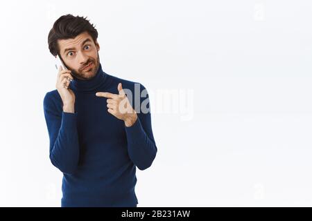 Guy explique qu'il s'est occupé de parler au téléphone avec un partenaire, en demandant de raccrocher et d'attendre jusqu'à ce qu'il termine la conversation. Bel homme d'affaires réussi dans le haut cou Banque D'Images