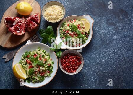 Salade saine avec couscous, menthe fraîche, concombre, grenade, citron et huile d'olive. Cuisine orientale. Concept alimentaire végétalien. Cuisine israélienne traditionnelle Banque D'Images