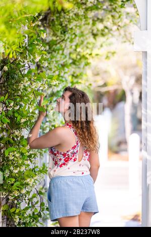 Jeune fille femme en été, le jour ensoleillé dans le jardin qui frayent des fleurs de plantes de vigne à l'extérieur, porte la mode pastel Banque D'Images