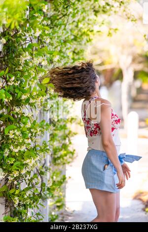 Jeune femme adulte fille personne rotation tourner mouvement en été le jour ensoleillé dans jardin plante de vigne fleurs à l'extérieur du jardinage et porter la mode pastel Banque D'Images