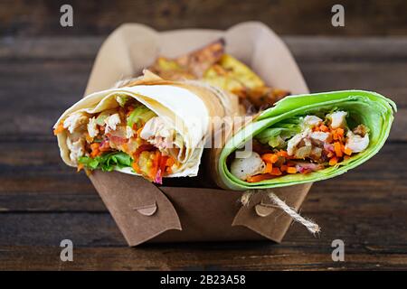 Délicieux sandwich au shawarma avec poulet et pomme de terre sur fond en bois Banque D'Images