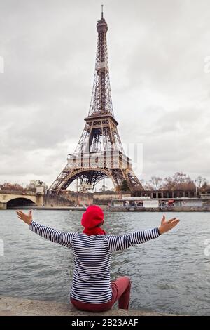 L'homme est assis sur le bord d'une rivière et ressemble à la Tour Eiffel Banque D'Images