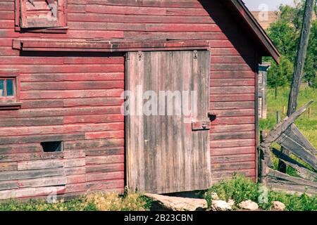 Gros plan sur l'avant d'une ancienne grange rouge abandonnée avec porte et porte coulissante Banque D'Images