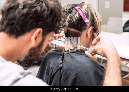 Le coiffeur de maître coupe les cheveux de femme blonde dans le salon. Gros plan de la photo. Banque D'Images