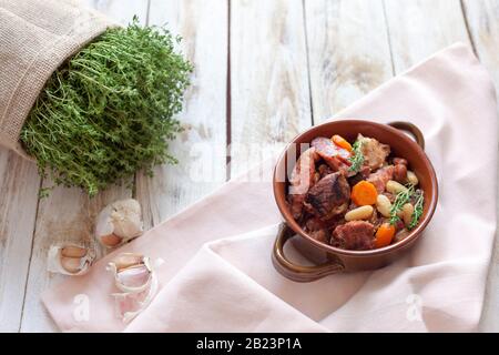 Cassoulet. Contenant des saucisses de porc à la viande, des oies, des canards et parfois des mutons et deux types de haricots blancs. Cuisine française (cuisine). Banque D'Images