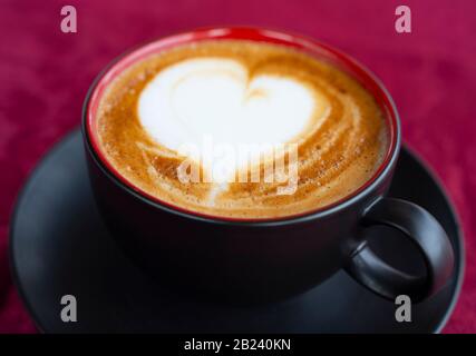 Tasse de café en forme de coeur sur fond rose. Banque D'Images