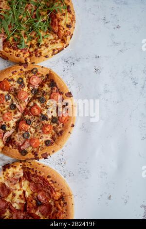 3 différents types de pizzas placés dans une ligne blanche sur table rouillée Banque D'Images