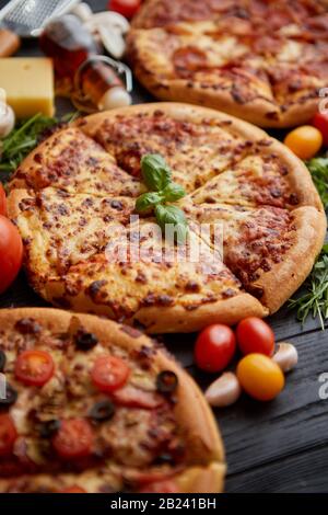 Servi frais, trois différentes pizzas placé parmi des ingrédients savoureux. Vue d'en haut Banque D'Images