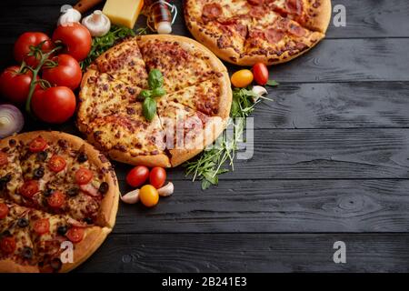 Servi frais, trois différentes pizzas placé parmi des ingrédients savoureux. Vue d'en haut Banque D'Images