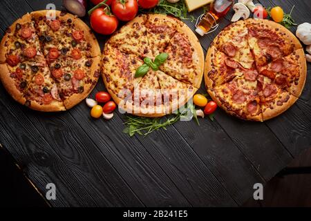 Servi frais, trois différentes pizzas placé parmi des ingrédients savoureux. Vue d'en haut Banque D'Images