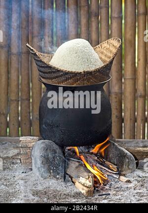 Cuiseur à riz traditionnel au feu ouvert, cuisson à base de riz collant dans un panier de bambou au-dessus de l'eau de simmering, Farrm de riz vivant à terre près de Luang Prabang, Laos Banque D'Images