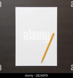 Modèle de papier blanc et crayon sur fond en bois de couleur wenge sombre. Concept de plan d'affaires et de stratégie, développement et mise en œuvre du contenu. Stocker la photo avec un espace vide pour le texte. Banque D'Images
