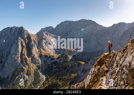 Mountaineer avec casque d'escalade se tient sur un affleurement rocheux, sentier de randonnée à l'Ehrwalder Sonnenspitze, Ehrwald, Mieminger Kette, Tyrol, Autriche Banque D'Images