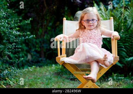 Portrait fille de 3 ans assise dans une chaise de jardin, République tchèque Banque D'Images