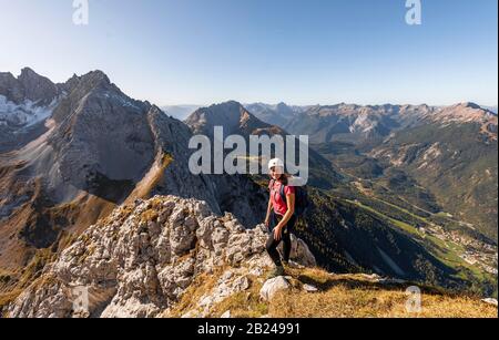 Jeune femme, alpiniste avec casque d'escalade regardant le paysage de montagne, randonnée à Ehrwalder Sonnenspitze, derrière Gruenstein et l'ouest Banque D'Images