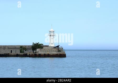 Balise montée sur le bord de la jetée en béton au port de Yalta, qui se bloque partiellement de l'entrée de la baie de Yalta. Coucher De Soleil Banque D'Images