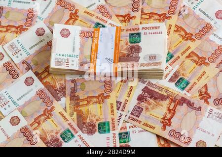 Le pack de cinq millième ruble notes dans un demi-million de roubles dans le forfait de services bancaires est sur l'arrière-plan de billets épars Banque D'Images