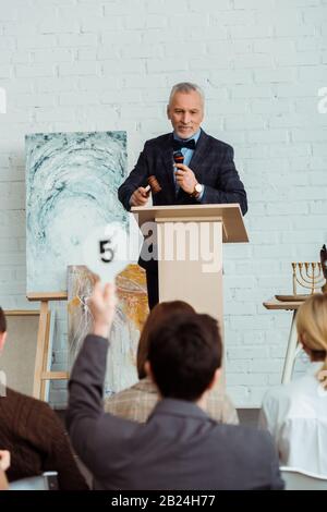 objectif sélectif de sourire auctioneer parler avec le microphone et regarder l'acheteur pendant la vente aux enchères Banque D'Images
