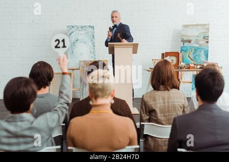 point de mire sélectif de l'encanteur tenant parler avec le microphone et regardant l'acheteur pendant la vente aux enchères Banque D'Images