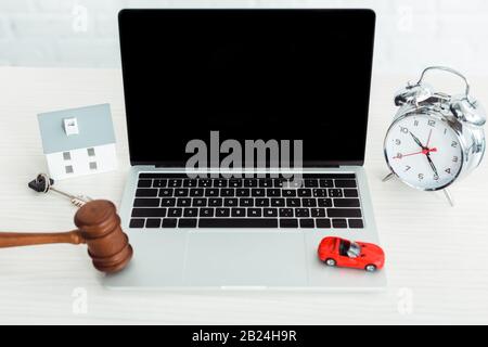 cavel en bois, modèles de voiture et de maison, clé, ordinateur portable, réveil sur table Banque D'Images