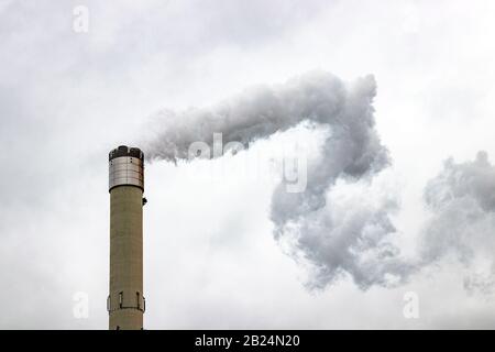 La grande cheminée émet des gaz dans l'atmosphère, provoquant la pollution de l'air. Gris, ciel nuageux. Banque D'Images