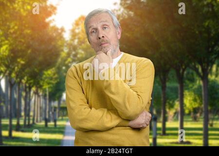 Portrait de l'homme réfléchi dans le parc avec fond vert. Banque D'Images