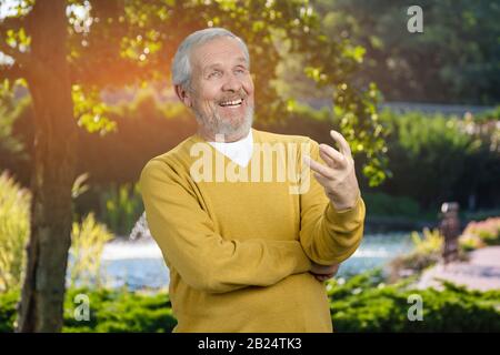 Un vieil homme qui parle avec quelqu'un en plein air. Banque D'Images