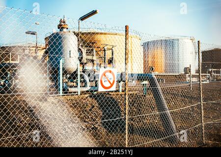 Pas de vue sur les panneaux de signalisation des grands réservoirs de stockage pétrochimiques pour les combustibles et les produits chimiques protégés par une grande clôture en fil Banque D'Images