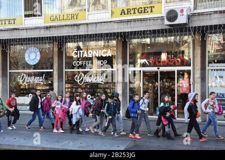 Les petits étudiants marchent dans une colonne sur la rue Banque D'Images