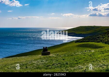 Des collines verdoyantes et herbeuses le long de la côte Dorset au-dessus de Dancing Ledge avec des ramblers prenant un repos et imprégnant de la vue Banque D'Images