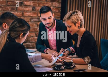 Divers collègues, partager leurs idées sur le projet et analyser les statistiques et la stratégie tout en appréciant leur café dans un café. Banque D'Images