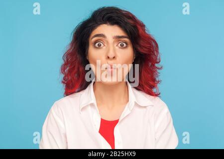 Portrait d'une femme hipster drôle avec des cheveux rouges fantaisie et s'est demandé l'expression faisant face de poisson, regardant ridicule confus, montrant ridicule stupide grimace Banque D'Images