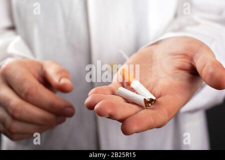 le médecin tient une cigarette cassée dans sa main. dommage causé par le tabagisme. maladie du cancer du poumon mal causé par la nicotine. Banque D'Images