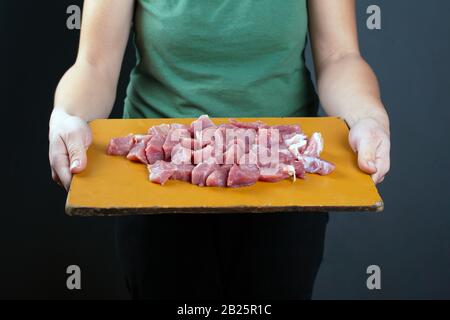 fille tenant la viande hachée sur une préparation de planche en bois pour la cuisson sur fond sombre. Banque D'Images