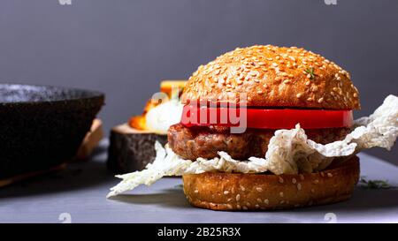 hamburger classique maison avec chou chinois, côtelette juteuse et poivre sucré sur fond gris. Banque D'Images