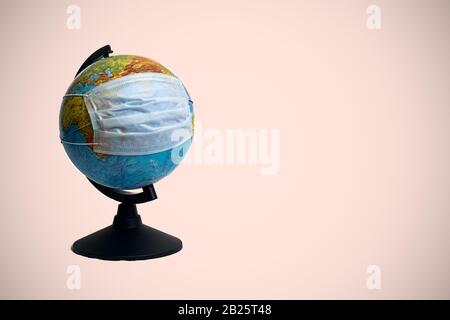 Globe dans le masque de protection médicale sur fond rouge, espace de copie Banque D'Images