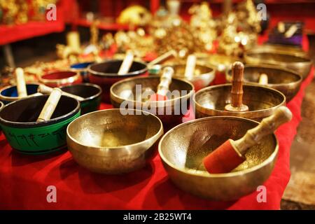 Des bols de chant tibétain d'or sur des comptoirs avec un tissu rouge du marché de nuit Goa Inde Banque D'Images