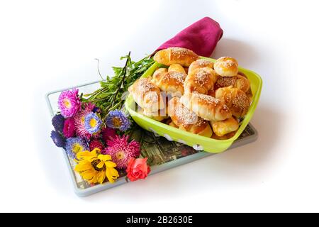 Petits pains au fromage, frais, croquants et chauds, servis avec amour, avec un grand bouquet de fleurs de champ, sur fond blanc Banque D'Images