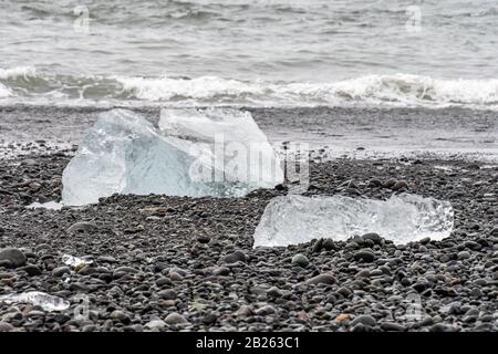 Plage de diamants sable noir cristal clair morceaux de glace couché sur des roches sombres Banque D'Images