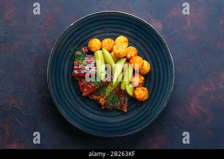 Vue de dessus des côtes grillées avec concombre mariné et boulettes de pommes de terre frites Banque D'Images