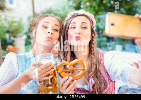 Best Friends in Bavarian Tracht faisant un avec le téléphone Selfies Banque D'Images