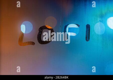 le mot lofi écrit par le doigt sur le verre humide de nuit de fenêtre, les couleurs bleu et orange Banque D'Images